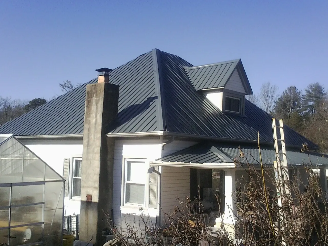Dark blue standing seam metal roof on a white farmhouse with dormer — Slate & Tile Roof Repair by Roofing Brothers in Tyner