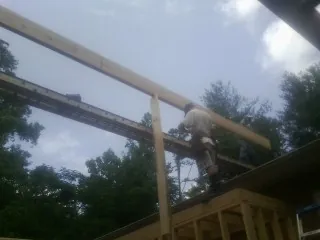 Carpenter setting a ridge beam over a new addition frame — Ice Dam Removal by Roofing Brothers in Tyner
