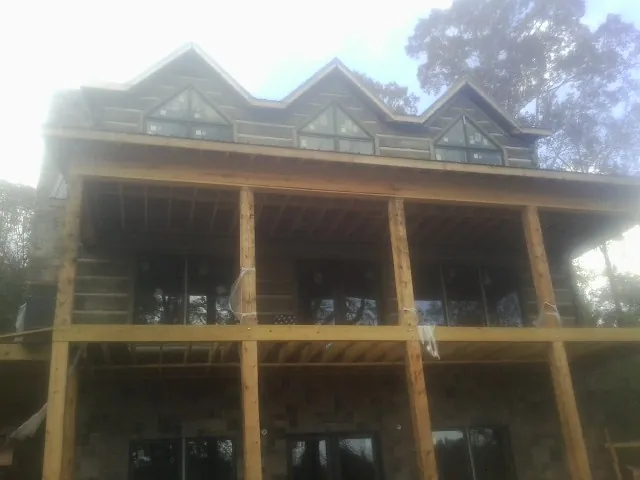 Dormers and porch framing on a large log home under construction — Roof Coating work by our crew in Tyner