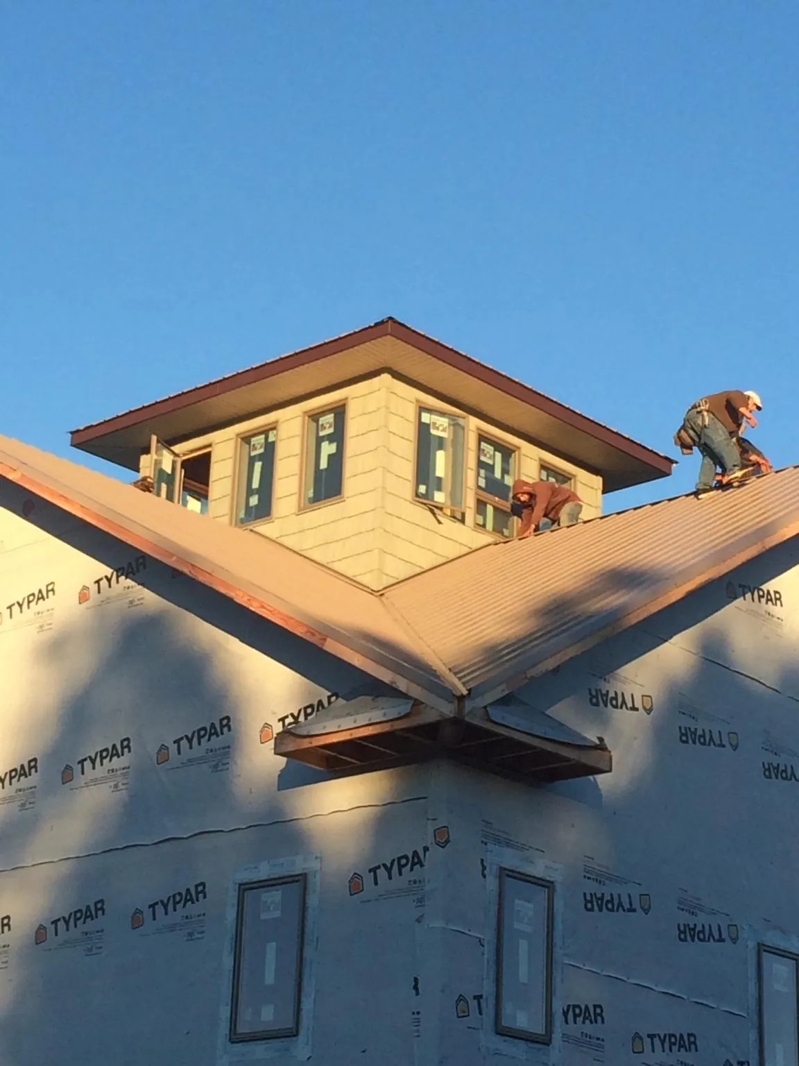 Roofers working around a rooftop cupola on a new metal roof at sunset — Roof Waterproofing in Tyner by Roofing Brothers